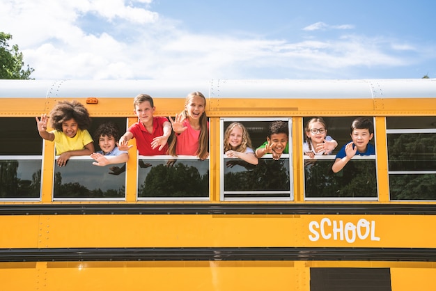 Photo group of young students attending primary school on a yellow school bus - elementary school kids ha1ving fun