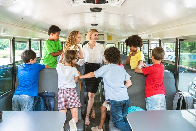 Group of young students attending primary school on a yellow school bus - Elementary school kids ha1ving fun