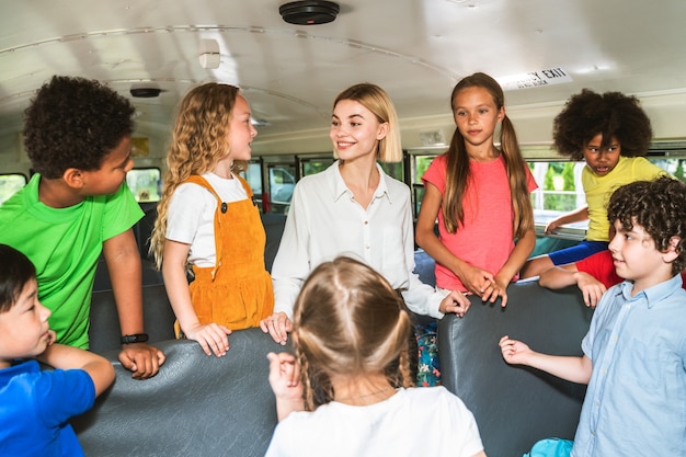 Group of young students attending primary school on a yellow school bus - Elementary school kids ha1ving fun