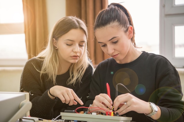 Group of young students doing technical vocational practice\
with teacher in the electronic classroom, education and technology\
concept