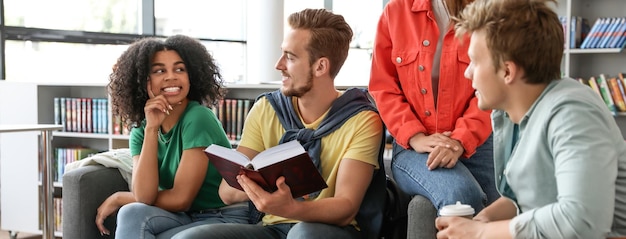 Group of young students at table in library Banner design