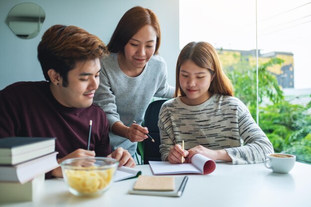 Group of young students tutoring and catching up workbook together