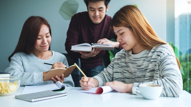 Group of young students tutoring and catching up workbook together