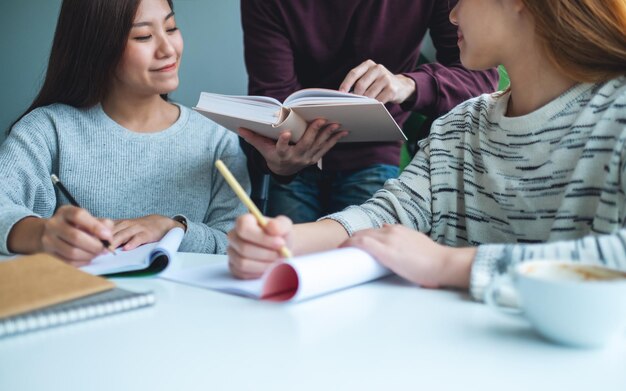 Group of young students tutoring and catching up workbook together