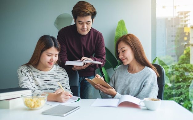 Group of young students tutoring and catching up workbook together