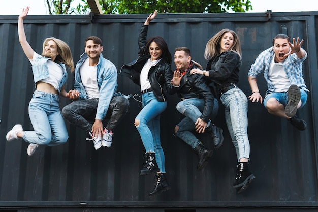 Photo group of young and stylish people jumping in the air on a city street