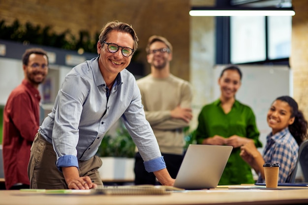 Group of young successful multi ethnic business team looking at camera and smiling while having