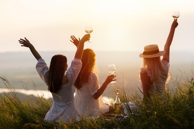 Photo group of young women sitting on grass on summer evening