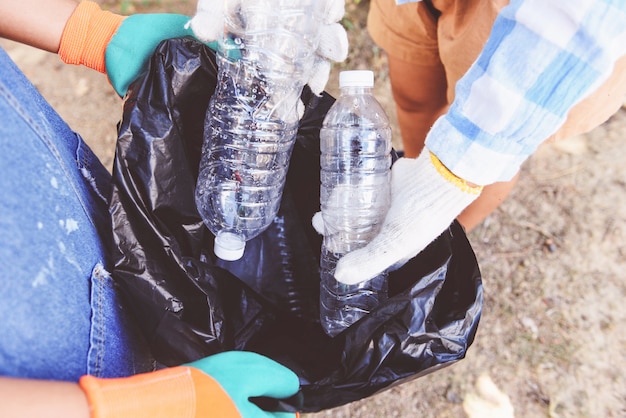 Group of young women volunteers helping to keep nature clean and picking up the garbage plastic bottle from park.