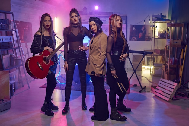 Group of young women with musical instruments standing in studio