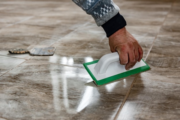 Photo grouting ceramic tiles. tilers filling the space between tiles using a rubber trowel.