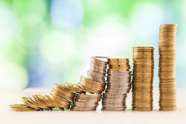 Growing coins stacks with green and blue sparkling bokeh . 