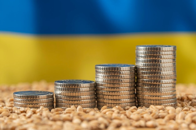 Photo growing money in the form of a stack of coins on the background of the ukrainian flag and grain wheat price grain reserves around the world food crisis export logistics solution
