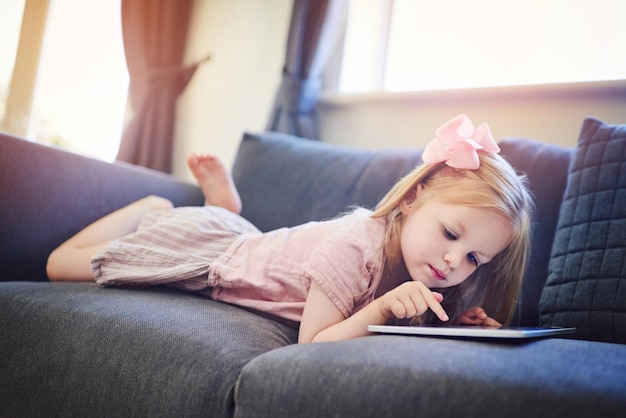 Growing up in a 4g world Shot of an adorable little girl using a digital tablet on the sofa at home