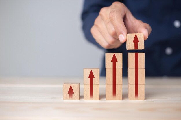 Growth graph and arrows ladder career path for business growth\
success process concept.hand arranging wood block stacking as step\
stair with arrow up.