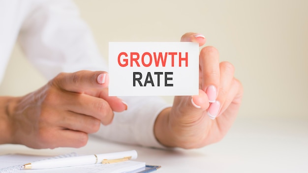 Growth rate word inscription on white card paper sheet in hands of woman. black and red letters on white paper. business concept, grey backgrond, pen and