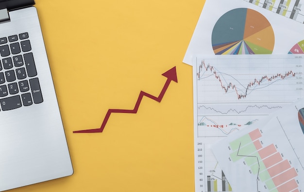 Growth upward arrow, graphs and charts with laptop on yellow. Online business. Business success