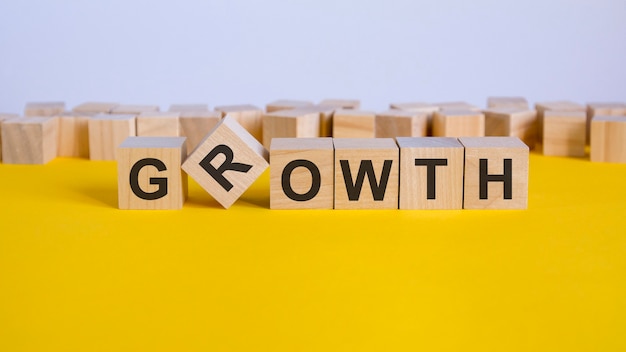 Growth word written on wood block. reduction word is made of\
wooden building blocks lying on the yellow table. business\
concept