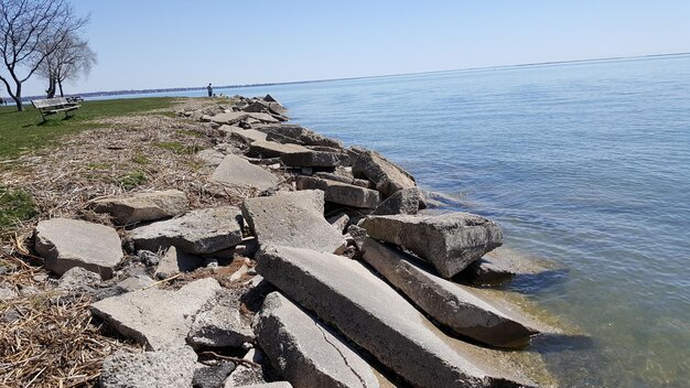 Groynes by sea against clear sky