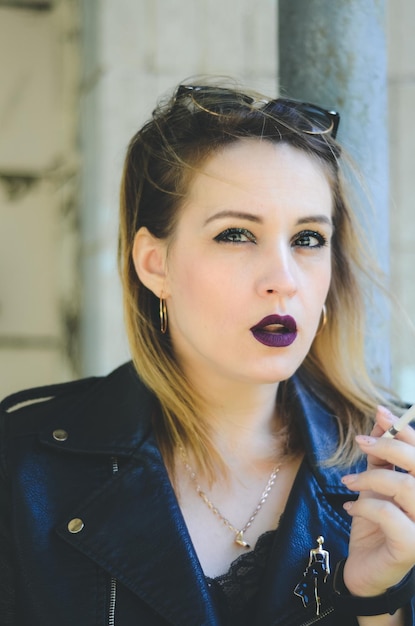 Grunge fashion portrait of stylish blonde woman,smoking cigar\
leather biker jacket, rock n roll mood