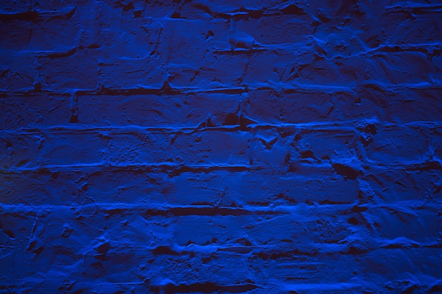 Grunge neon blue brick wall texture background.