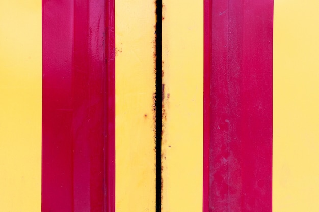 黄色と赤の縦縞のグランジ鋼ドア。金属境界での金属腐食
