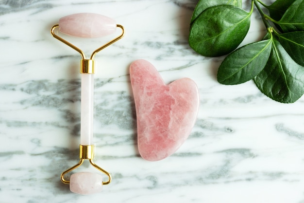 The gua sha and the face roller lie on the stone, flat lay