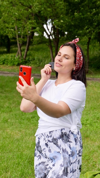 グアシャマッサージオンライン若いブルネットの女性が外の電話の前でクォーツガッシュスクレーパーで目の下でマッサージ代替医療と美容の概念垂直写真