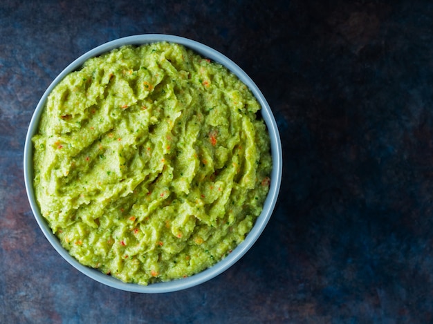 Guacamole in una ciotola grigia su sfondo scuro