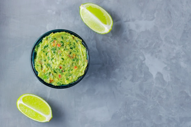 Guacamole kom op een grijze achtergrond. Traditionele Mexicaanse dipsaus guacamole in de kom. Mexicaanse keuken. Ruimte kopiëren. Bovenaanzicht