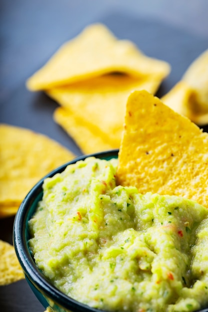 Photo guacamole and nachos chips on a dark background