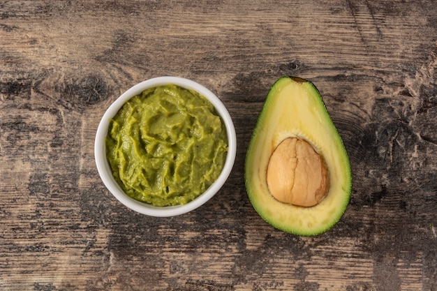 Guacamole sauce and avocado on wooden table