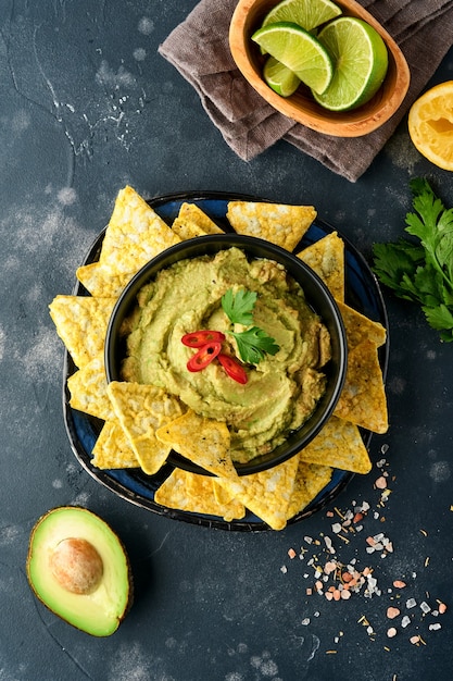 Guacamole. Traditional latinamerican Mexican dip sauce in a black bowl with avocado and ingredients 