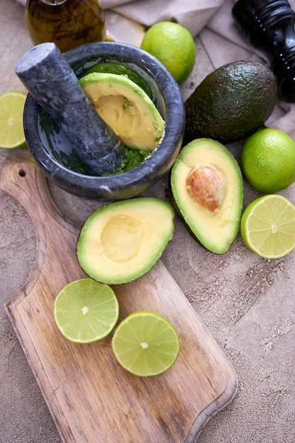 Guacamole vers gesneden avocado maken in marmeren vijzel op grijze betonnen tafel