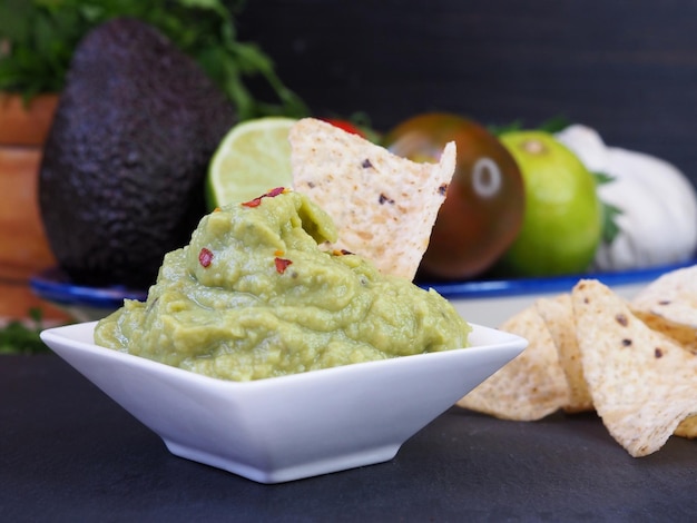 Guacamole in a white bowl and corn chips