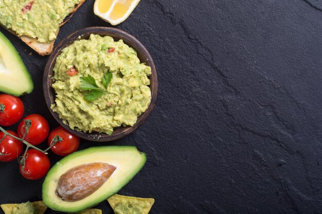 Guacamole with ingredients avocado lemon and tomatoes Mexican food