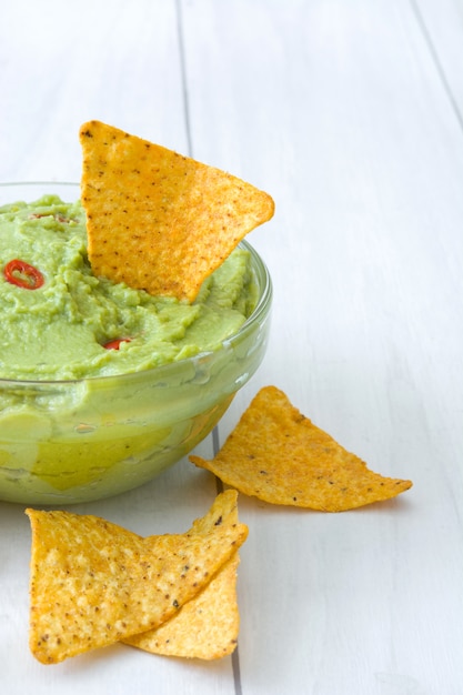 Photo guacamole with nachos on white wooden table