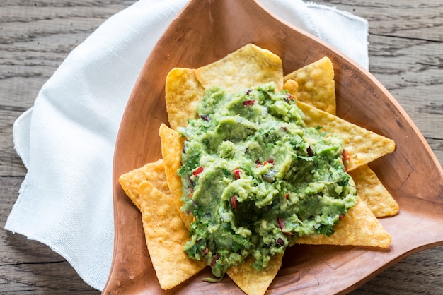 Guacamole with tortilla chips on the wooden background