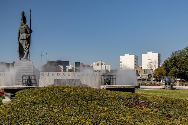 Guadalajara Jalisco Mexico 8 januari 2023 Glorieta Minerva met het standbeeld van de Romeinse godin in de fontein omringd door groene struiken tegen blauwe hemel gebouwen op de achtergrond op een zonnige dag