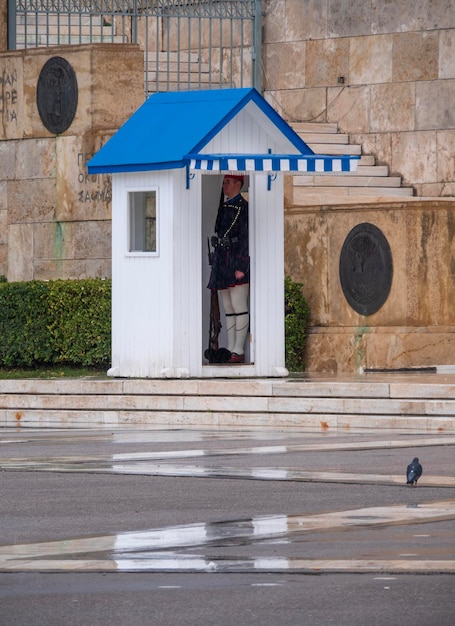 Guard of the Greek Evzon Guards at grave of Unknown Soldier on Syntagma Square in rainy weather