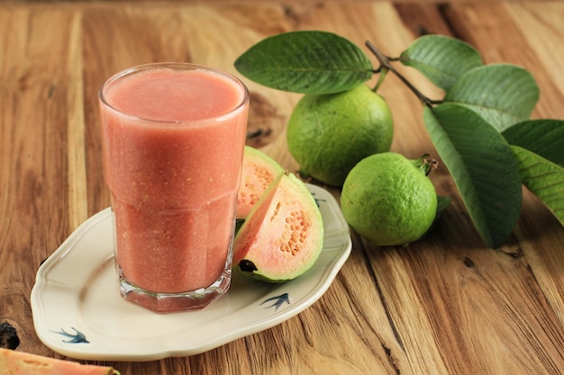 Photo guava juice on tall glass above wooden table