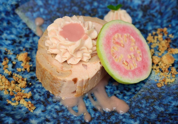 Guaiava roll cake su piatto blu su sfondo chiaro con frutta guava matura