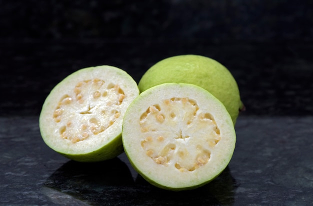 Guava, whole and sliced, on granite surface
