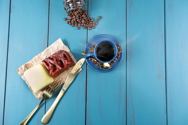 Guava zoet met kaas op een bruin papier omringd door bestekbonen en een kopje koffietop uitzicht