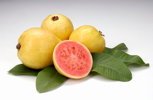 Guavas split in half and leaves on white background Tropical fruit