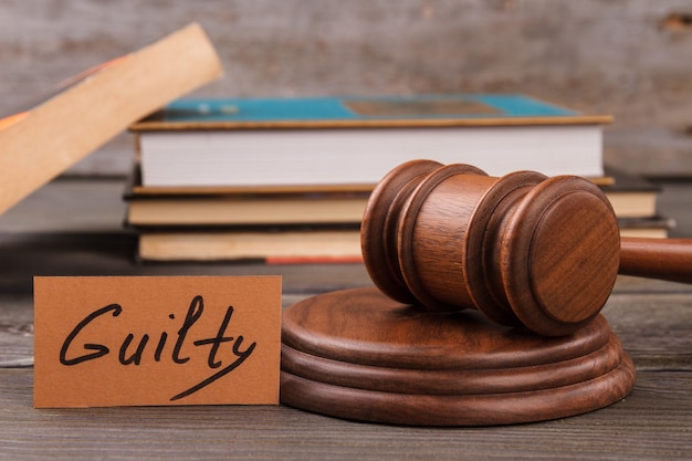 Photo gudge gavel and guilty verdict. stack of books on the background.