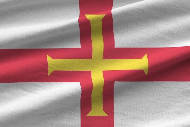 Guernsey flag with big folds waving close up under the studio light indoors The official symbols and colors in banner