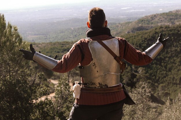 Photo guerrero medieval en el bosque, llevando una espada y una antorcha.