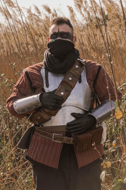 Guerrero medieval en el bosque, llevando una espada y una antorcha.