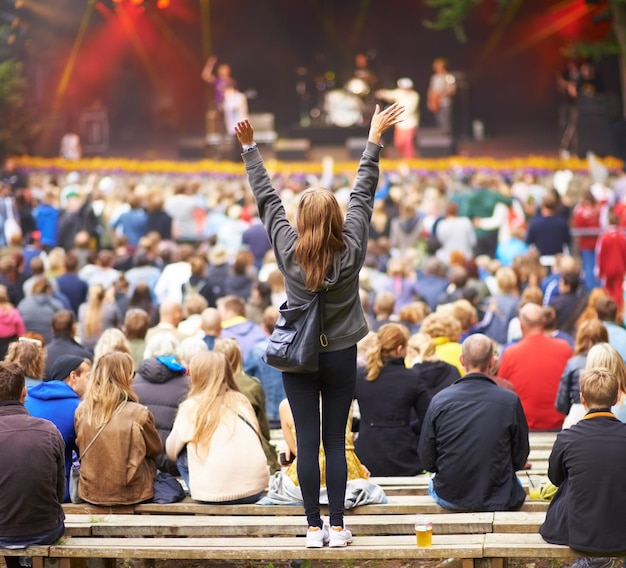 Guess whos her favourite band Rearview shot of a crowd at an outdoor music festival with the focus on a female fan cheering